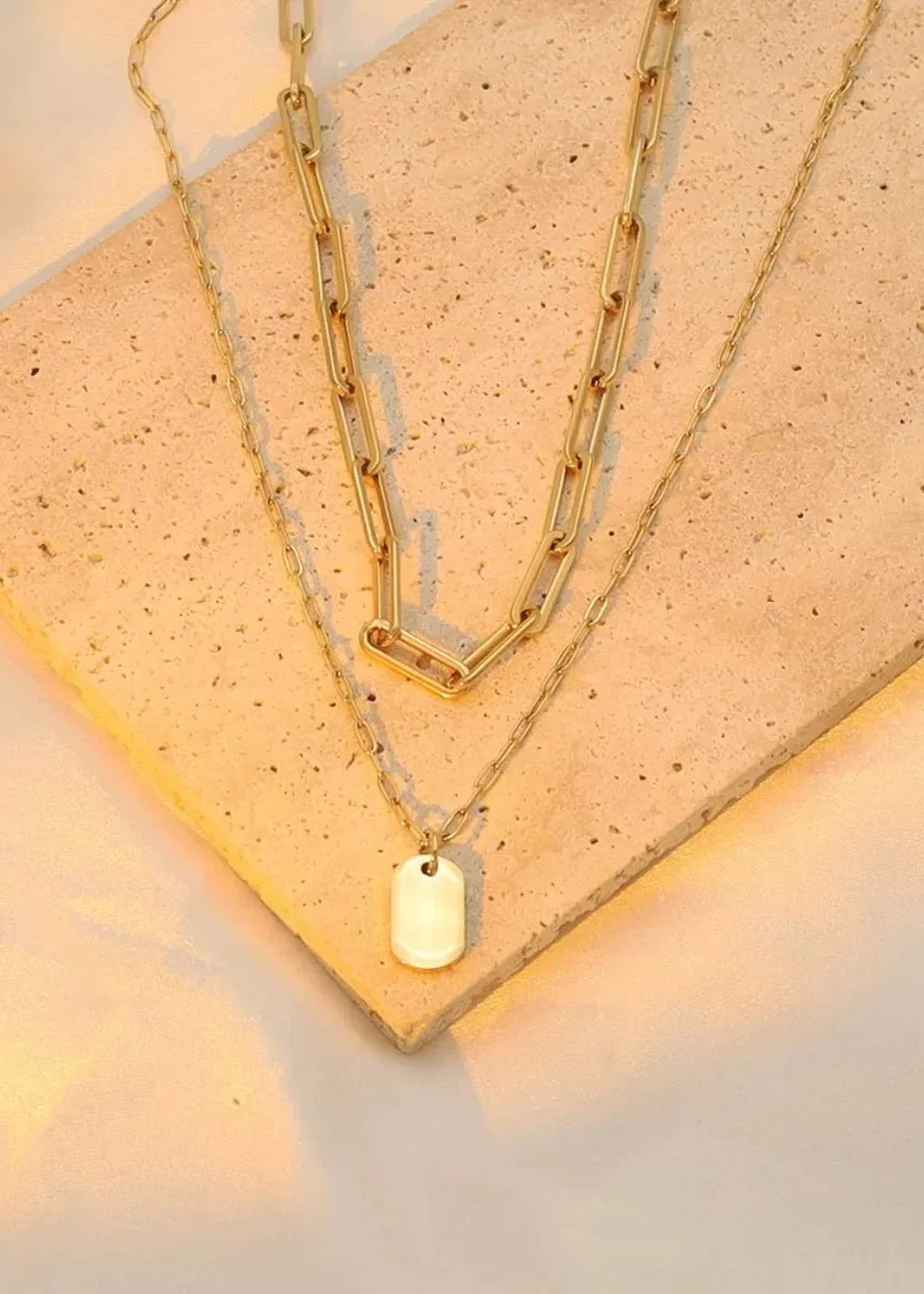 Gold-plated layered necklace with a large paperclip chain and a small dog tag pendant.