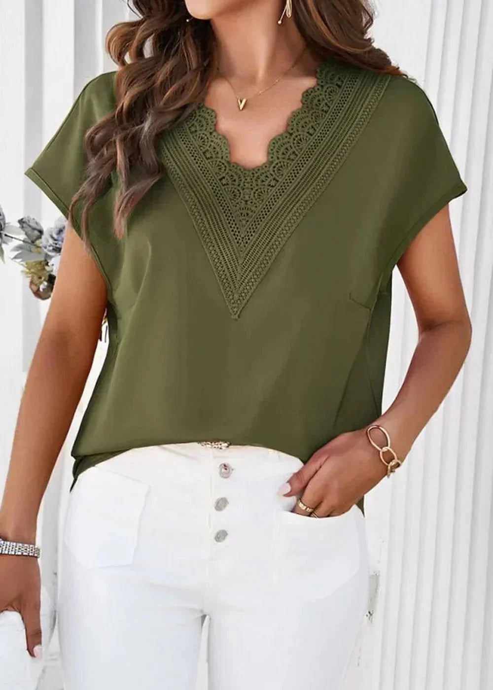 Olive green V-neck top with lace trim and short sleeves, paired with white button-fly pants.