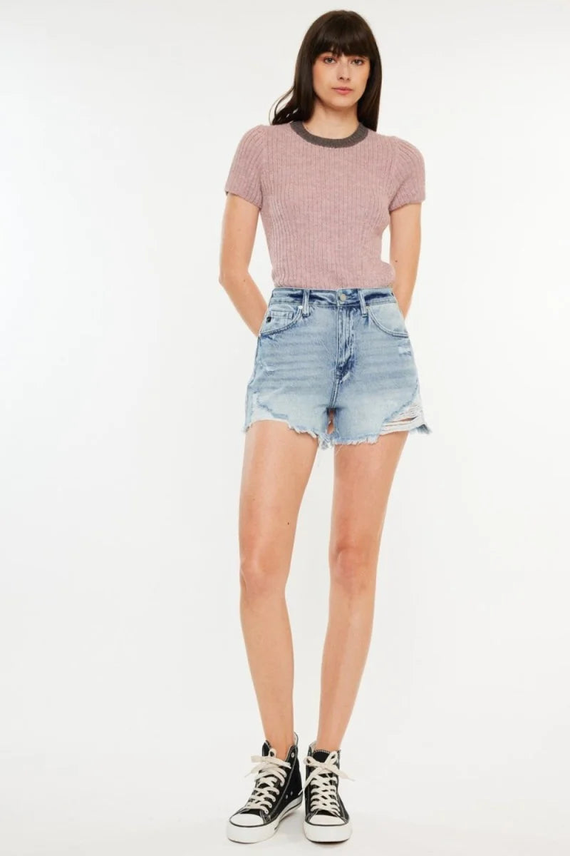Light wash denim shorts with distressed details and frayed hem, on a model.