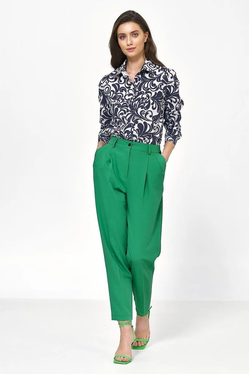 Emerald green pleated high-waisted pants with a relaxed fit and a cuffed hem, worn by a model.