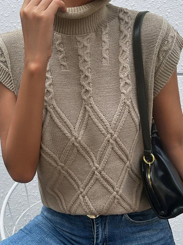 Close-up of a beige cable knit sleeveless turtleneck sweater with diamond pattern.
