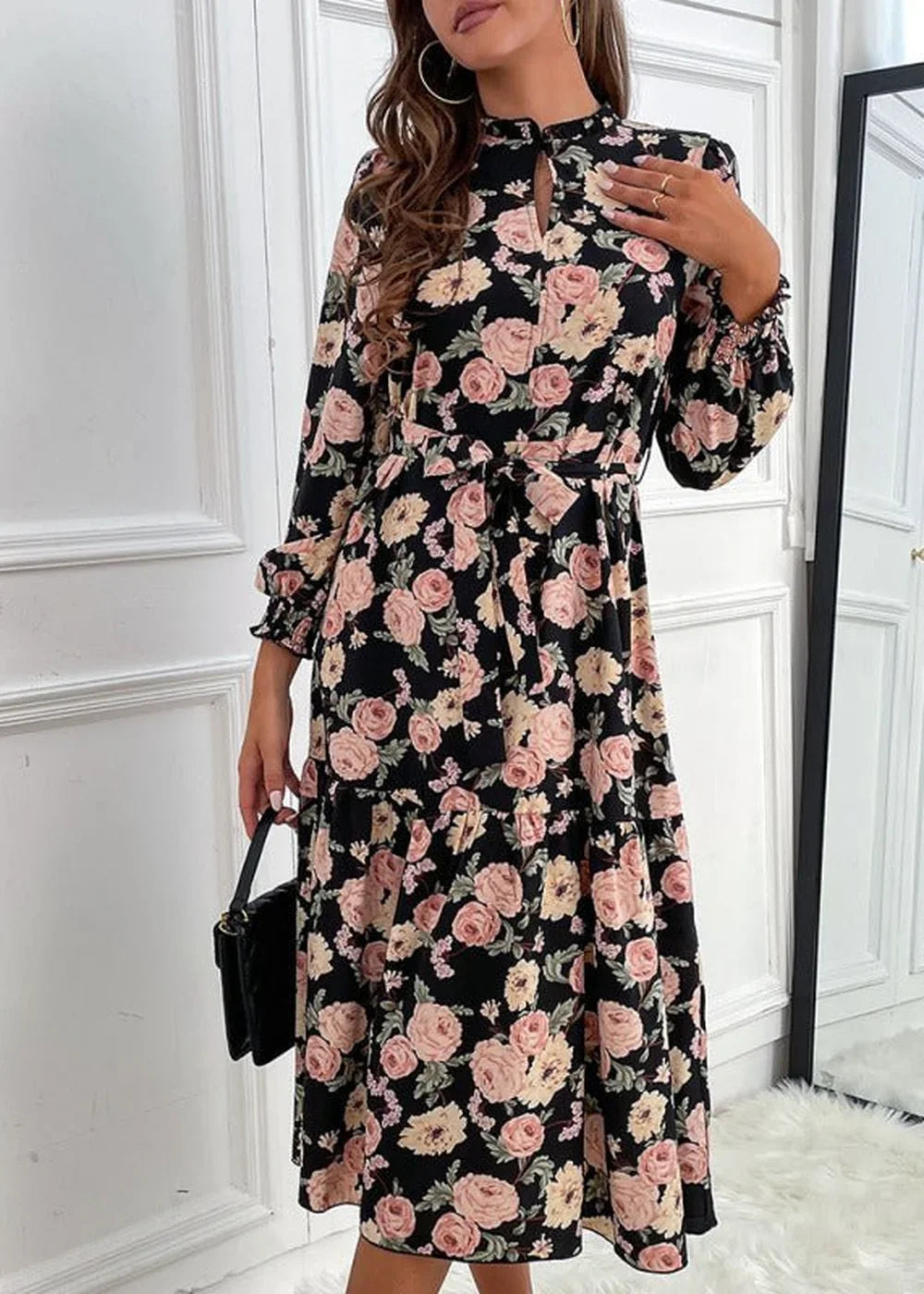 Black midi dress with a pink and cream floral pattern, long sleeves, and a belted waist.