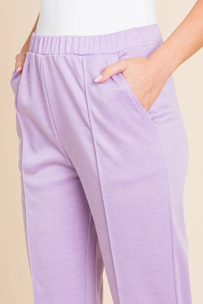 Close-up of lavender herringbone slim-fit pants with elastic waistband and pockets.