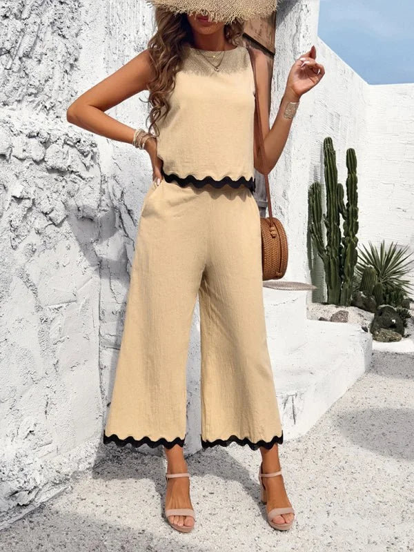 Tan wide-leg pantsuit with black scalloped trim on the hem and top, worn by a model.