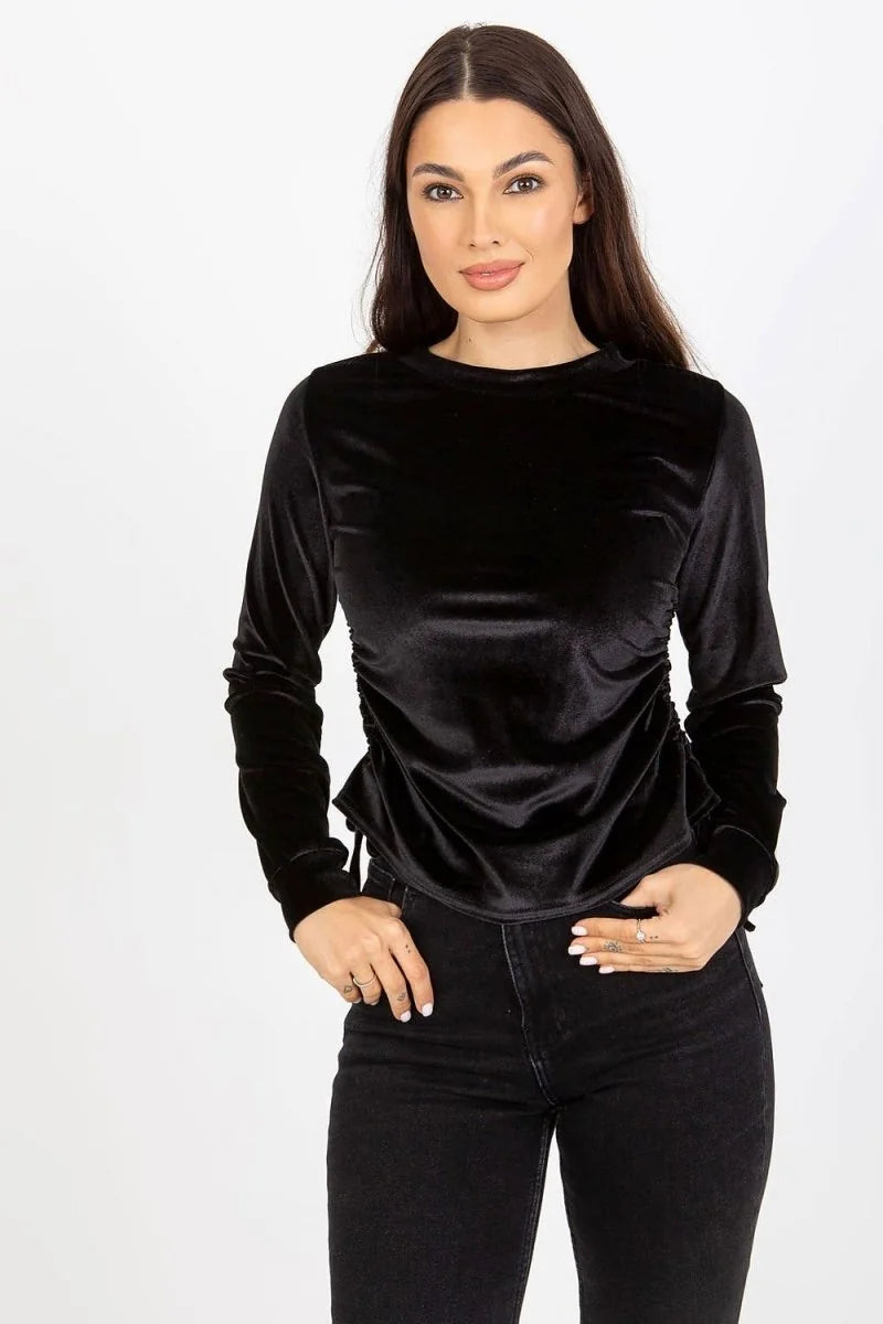 Black velvet long-sleeve top with ruched sides and cinched waist on a model.