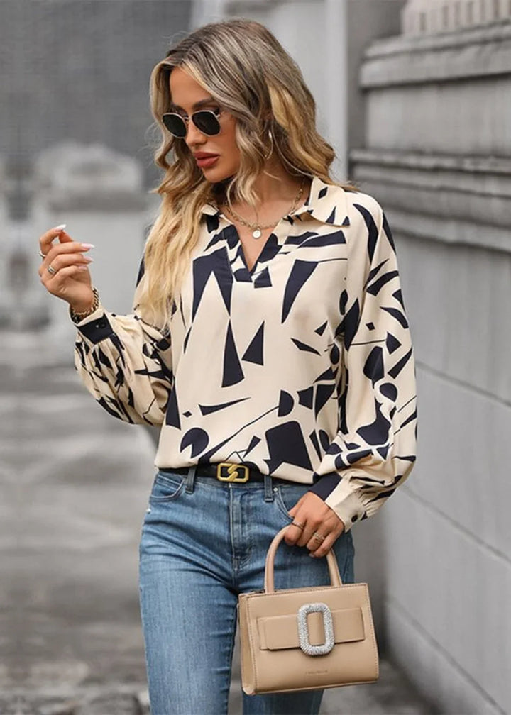 Cream and navy abstract print long-sleeve blouse with a collar and belted jeans.