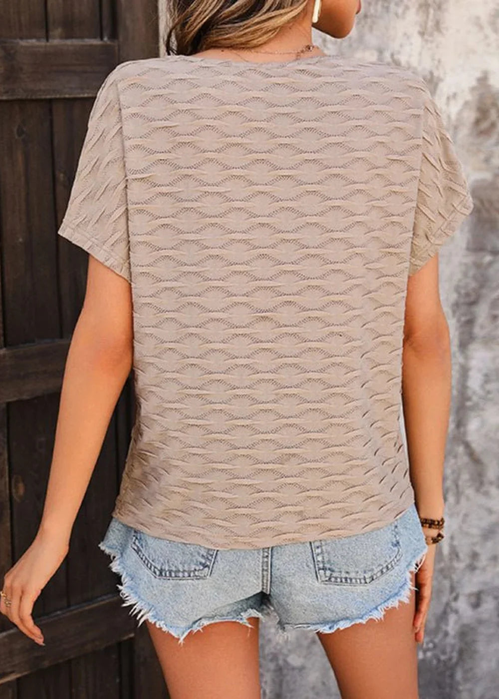 Beige textured knit top with short sleeves and frayed denim shorts.