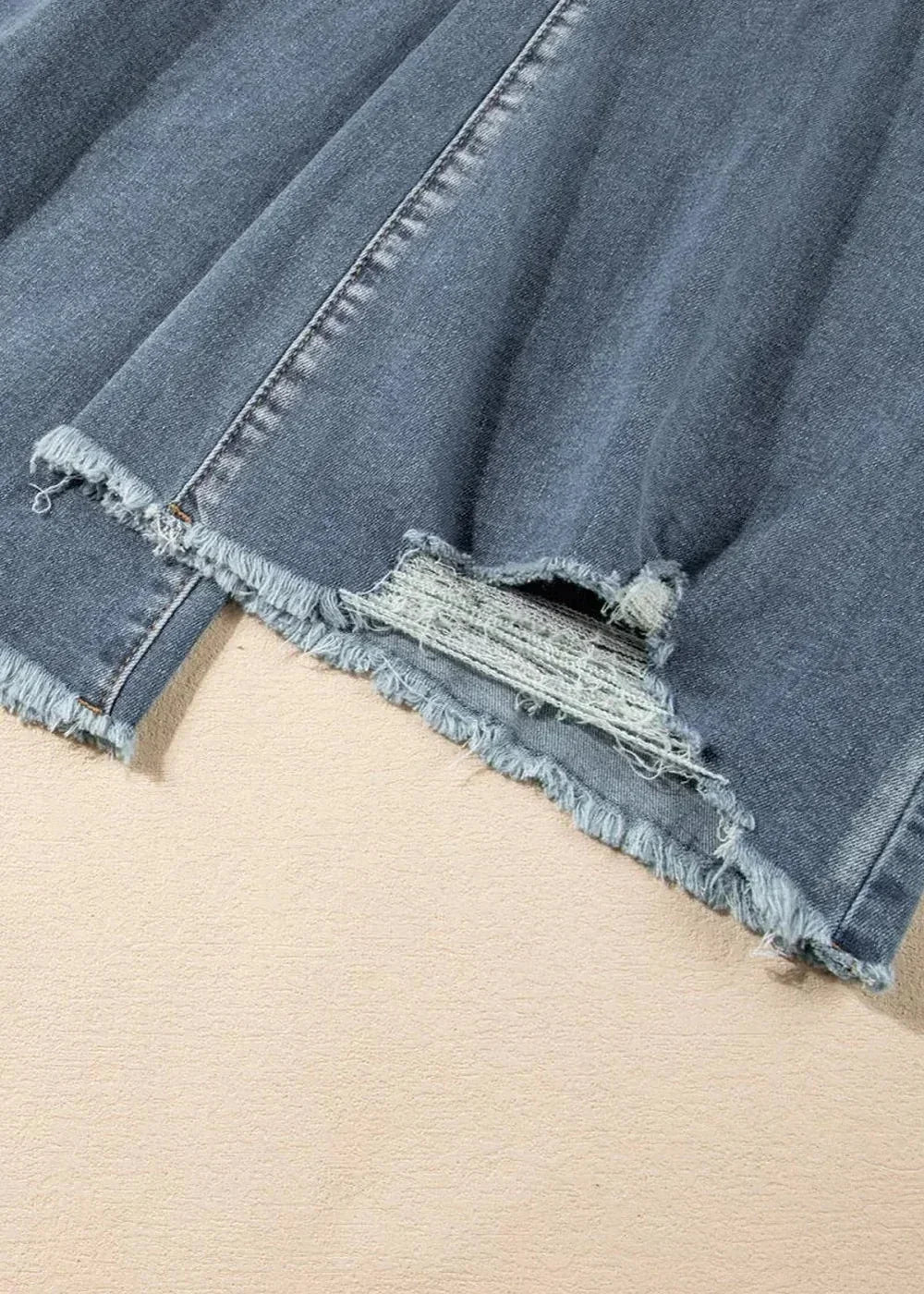 Close-up of distressed denim shorts with frayed hems and rips, showing texture.