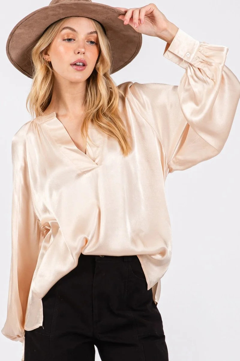 Cream satin blouse with V-neck, blouson sleeves, and button cuffs on a model.