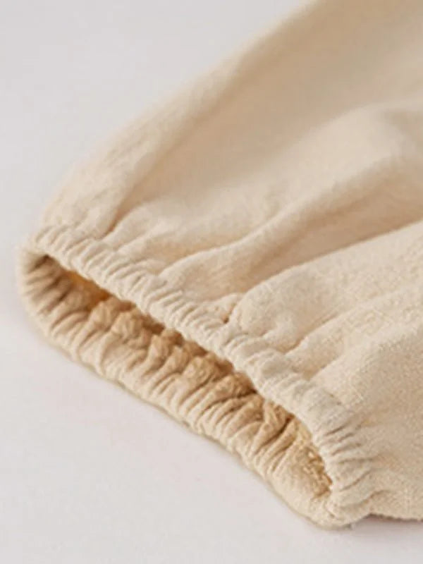 Close-up of a beige linen-blend fabric with an elasticized, gathered cuff.