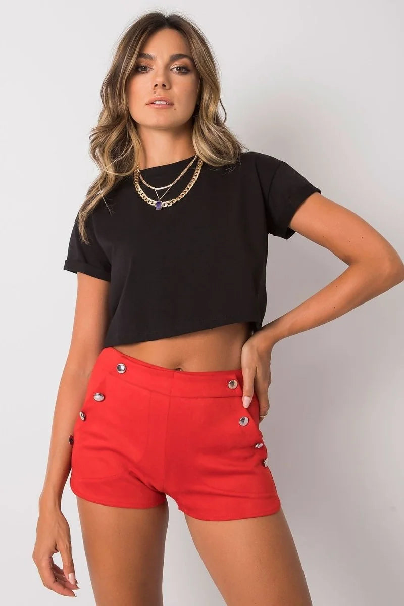Woman in black crop top and red high-waisted shorts with silver button details.