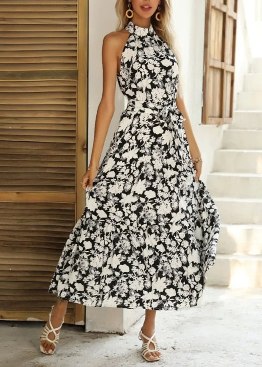 Black and white floral print halter maxi dress with a tie waist and tiered skirt.