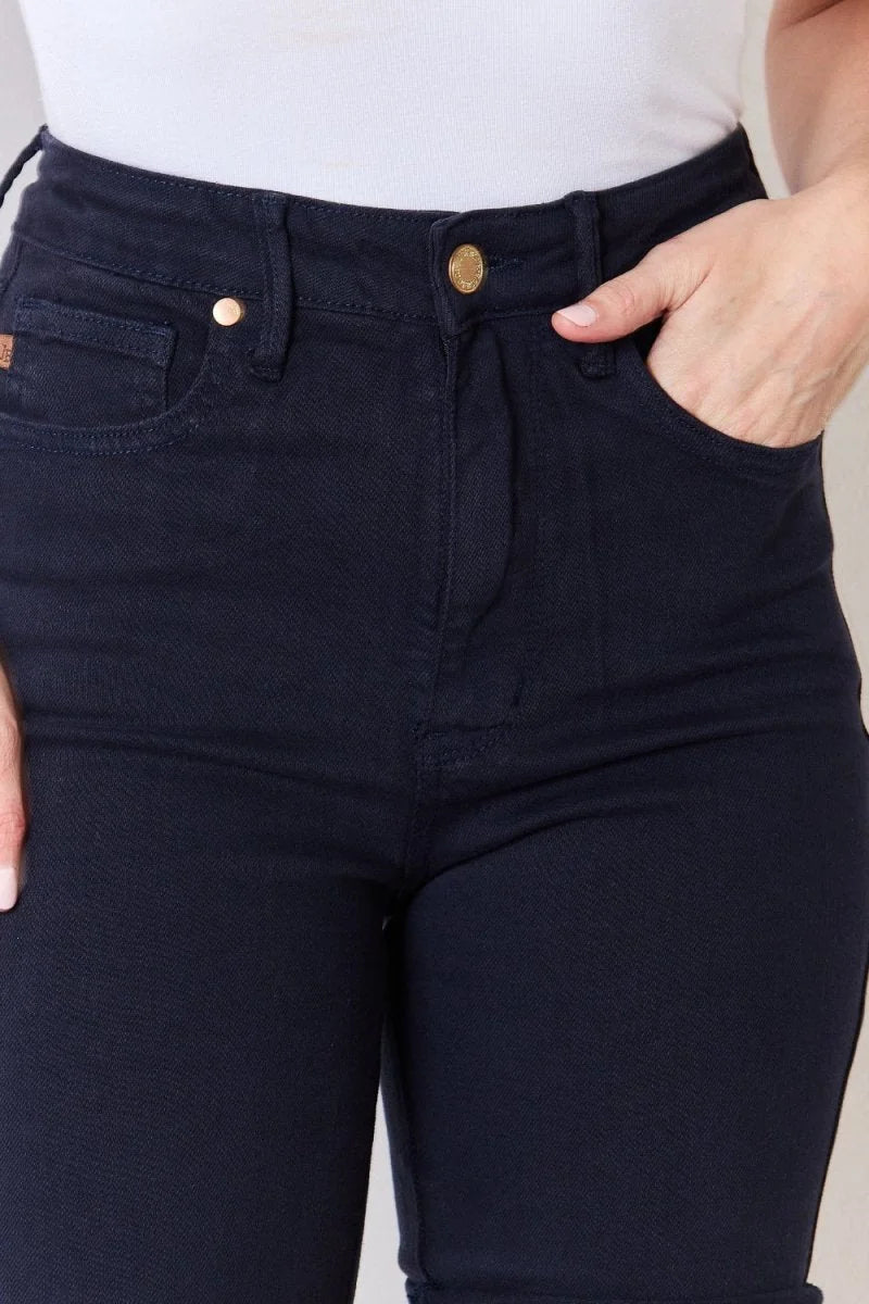 Close-up of navy blue cotton blend pants showing button closure and pocket detail.