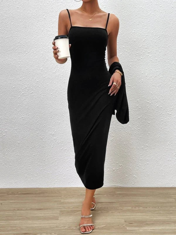 Black slip dress with a draped skirt, worn with strappy heels and a cardigan draped over the arm.