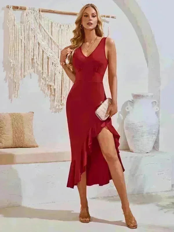 Red sleeveless V-neck dress with ruffled high-low hem and clutch bag, on model.