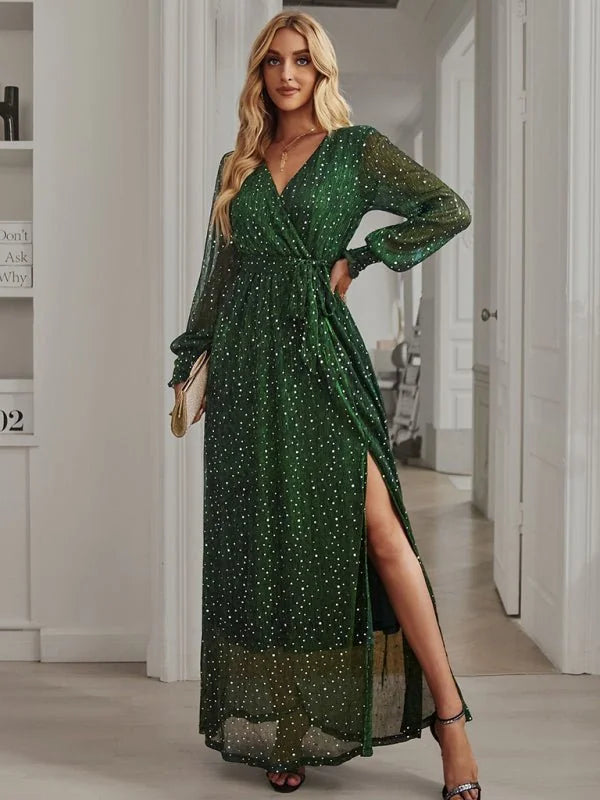 Emerald green sparkly maxi dress with a V-neck, wrap style, and high leg slit, worn by a model.