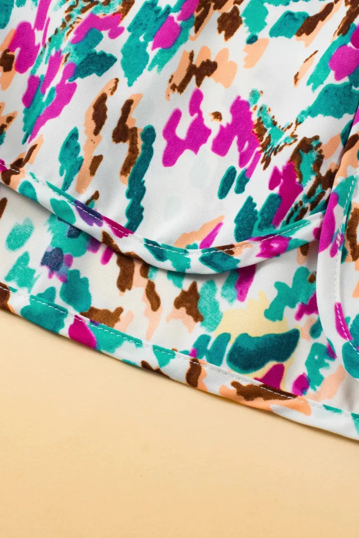 Close-up of white polyester fabric with a colorful abstract print in pink, teal, orange, and brown.