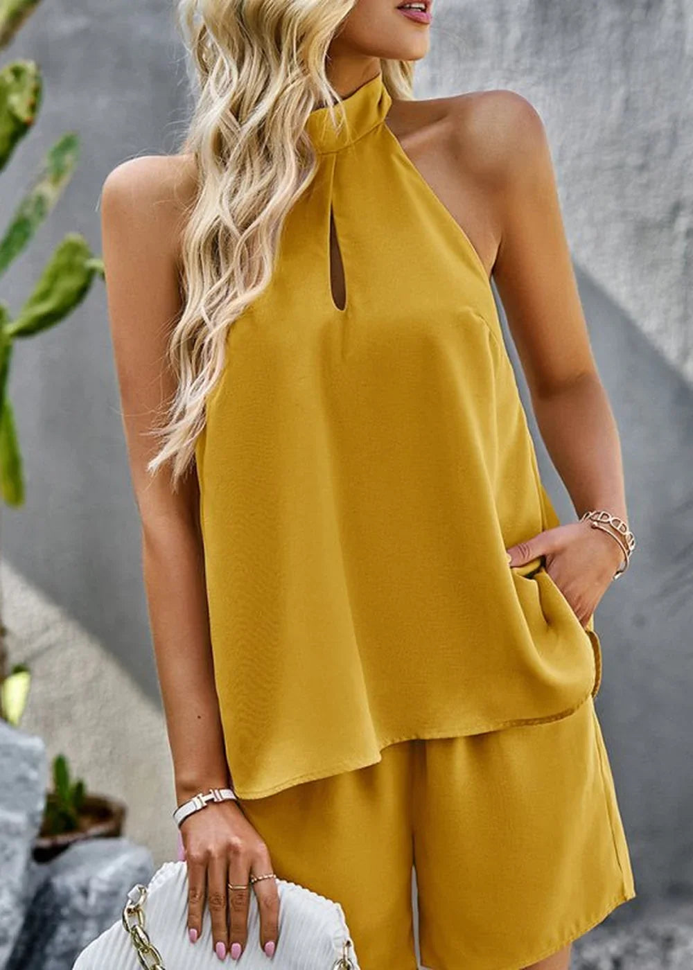 Woman in mustard yellow halter top and shorts set, with a keyhole neckline and pockets.