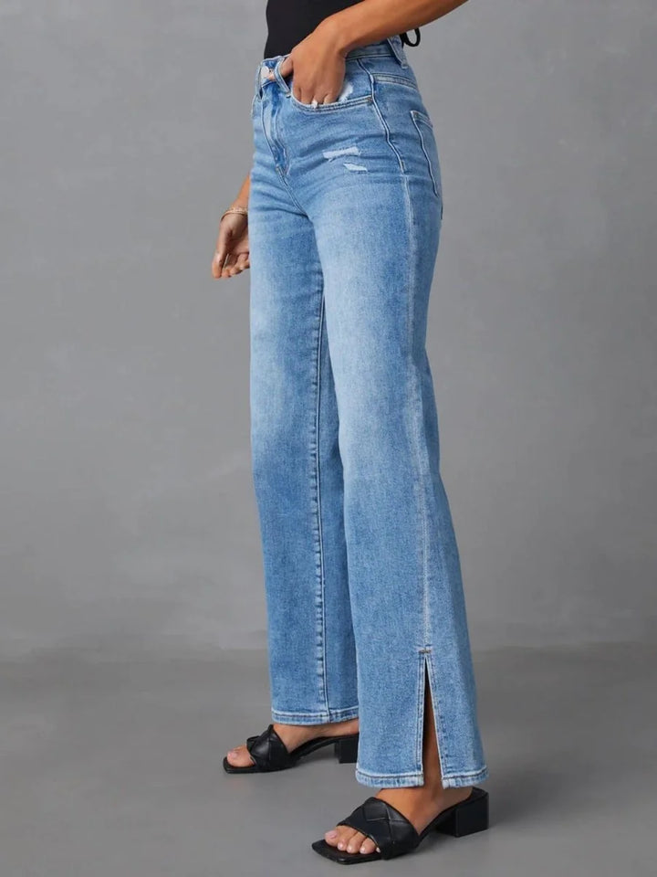 Light wash distressed denim jeans with a high waist and side slits, worn with black slide sandals.