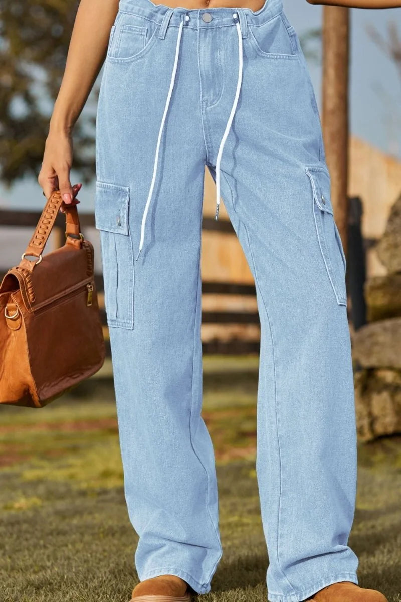 Light wash denim cargo pants with white drawstring and side pockets, on model.