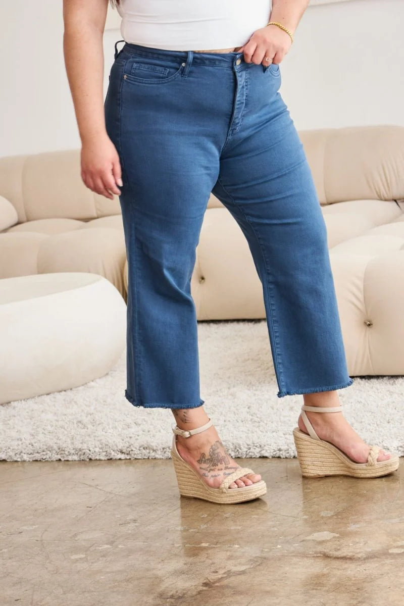 Woman in dark wash denim cropped flare jeans with frayed hem and espadrille wedges.