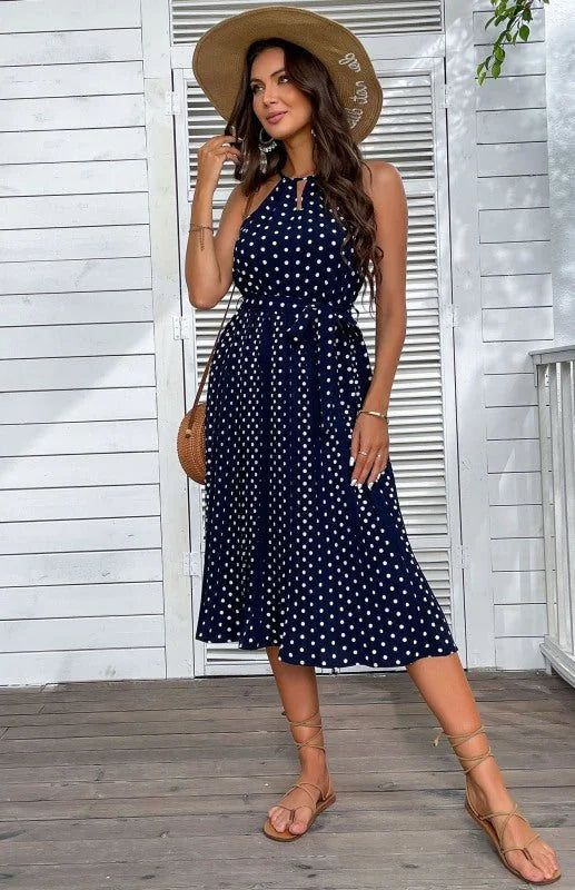 Navy blue polka dot midi dress with tie waist and lace-up sandals on model.