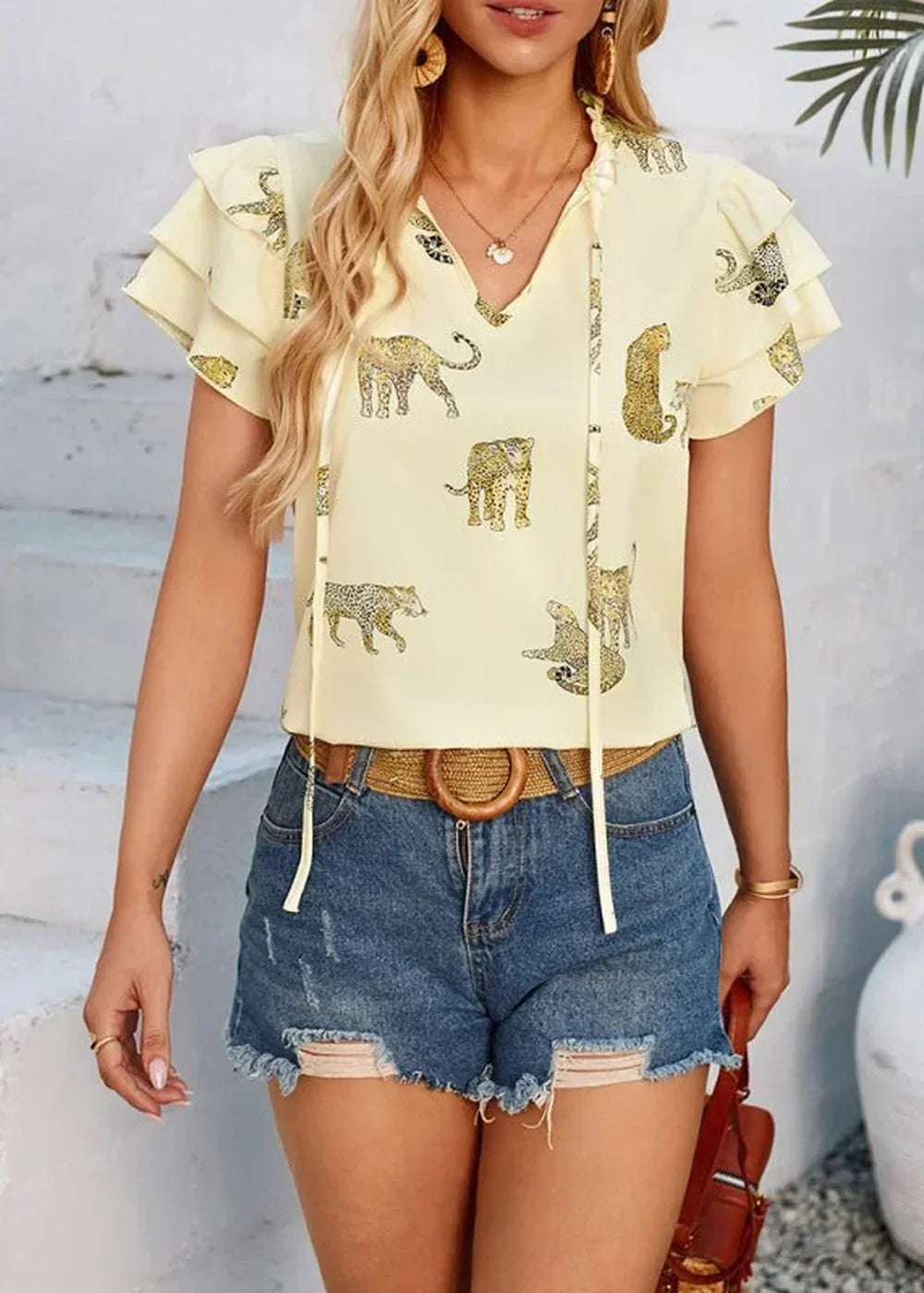 Yellow flutter sleeve top with leopard print, paired with distressed denim shorts.
