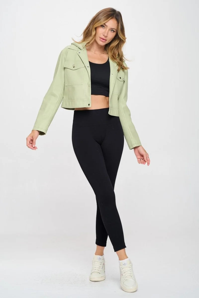 Light green vegan leather jacket with a hood and snap-button pockets, worn by a model with black leggings and white sneakers.