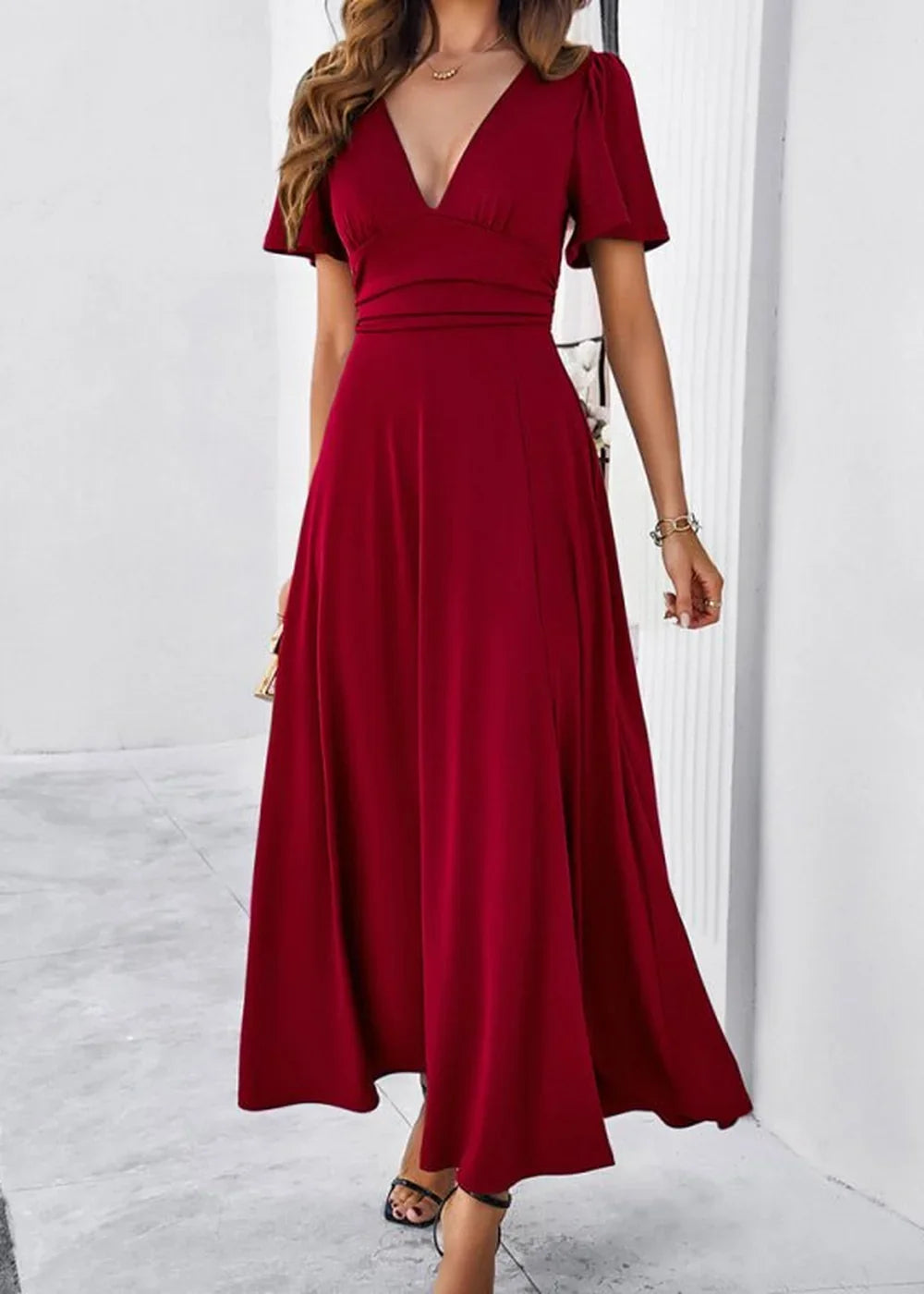 Wine red V-neck maxi dress with flutter sleeves and a flowy skirt, worn by a model.