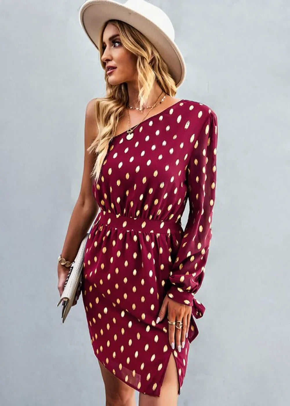 Burgundy one-shoulder dress with gold polka dots, cinched waist, and thigh-high slit on model.