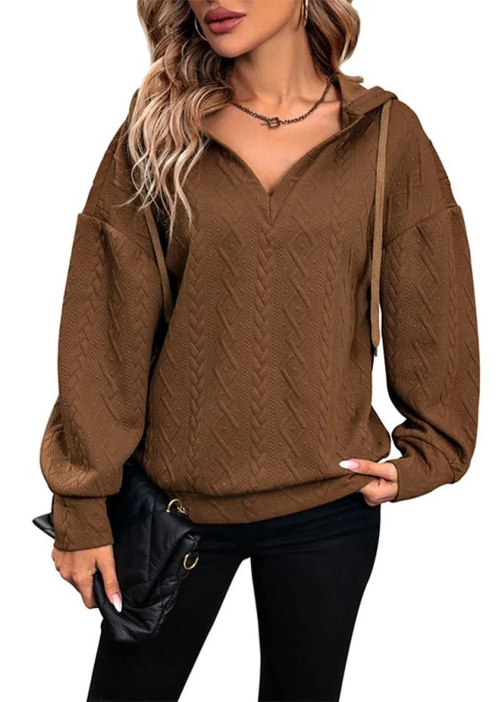 Brown textured hoodie with V-neck and cinched cuffs on a model holding a black clutch.
