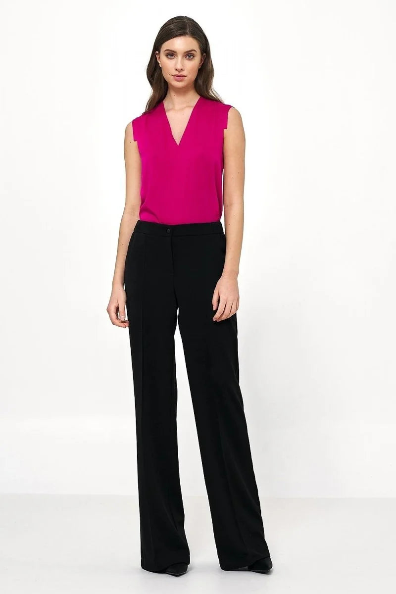 Full length shot of a woman wearing black, relaxed fit, wide-leg pants.