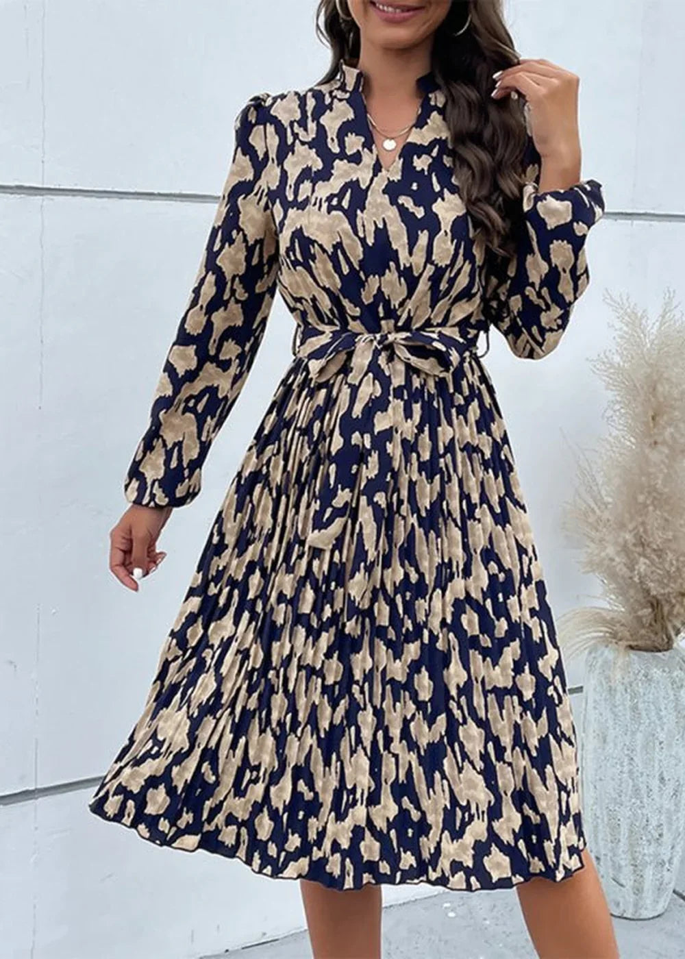 Navy and tan abstract print pleated midi dress with tie waist and long sleeves.