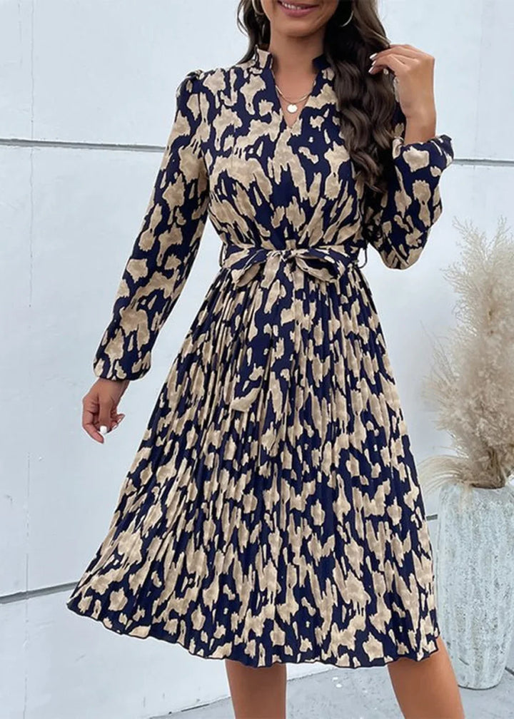 Navy and tan abstract print pleated midi dress with tie waist and long sleeves.