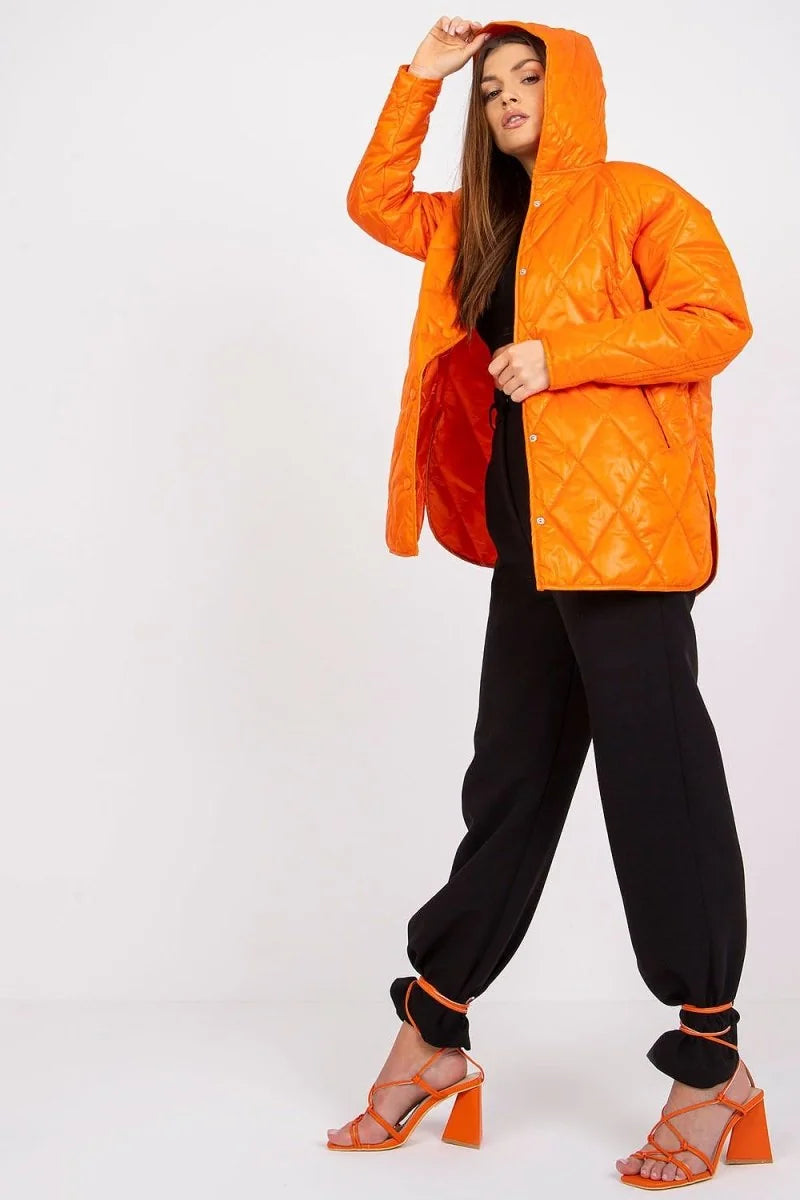 Orange quilted jacket with hood, worn by a model in black pants and orange heels.