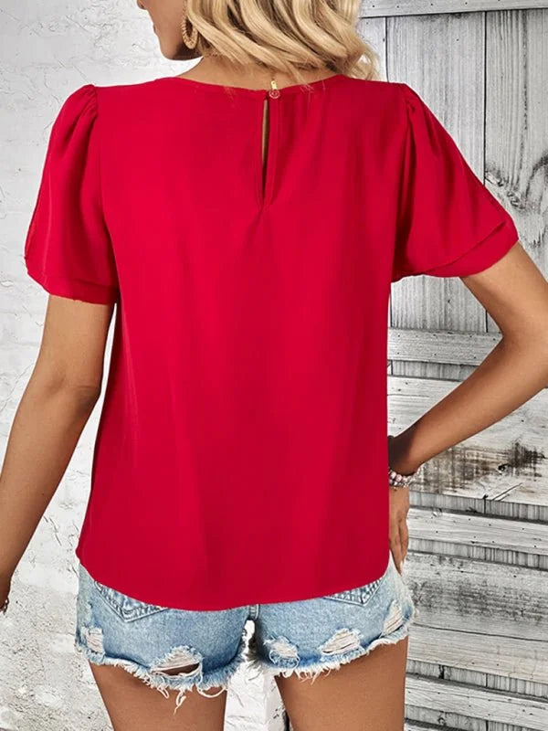 Red puff-sleeve top with button closure on back, paired with distressed denim shorts.