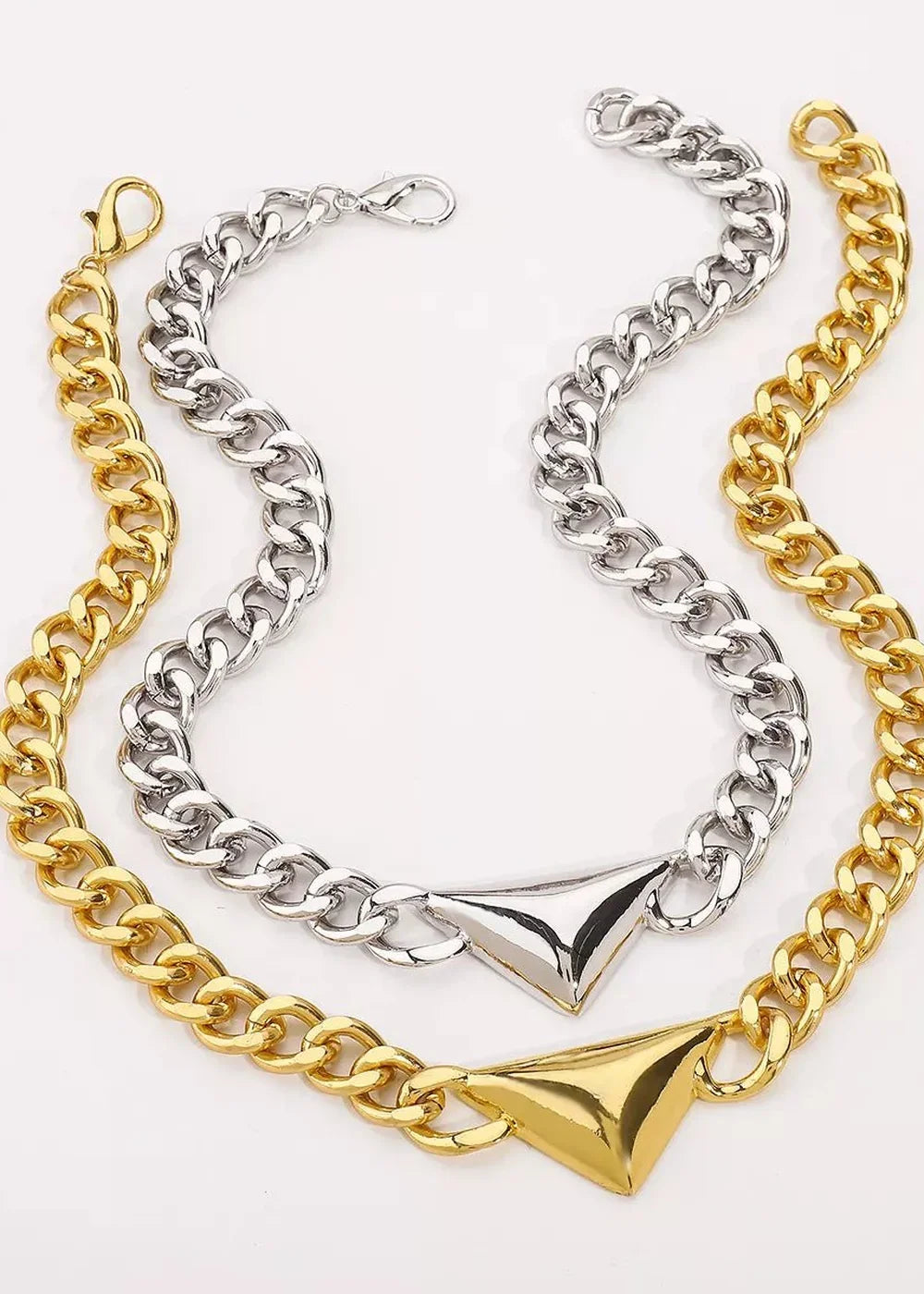 Gold and silver chunky chain necklaces with geometric triangular pendants.