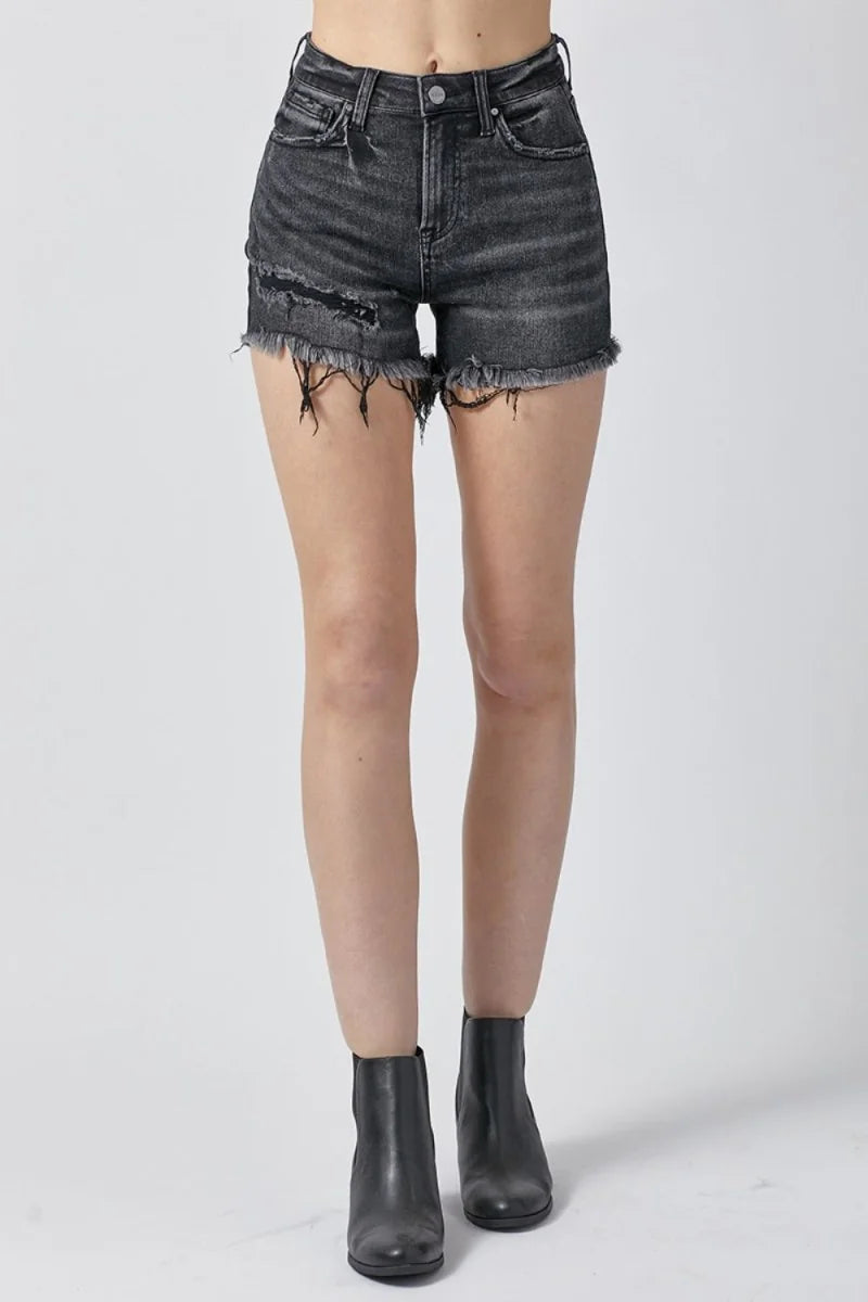 Distressed black denim shorts with frayed hem and ripped detailing, on model.