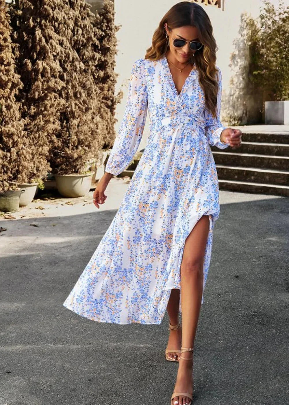 White maxi dress with a blue and orange floral pattern, long sleeves, and a thigh-high slit.