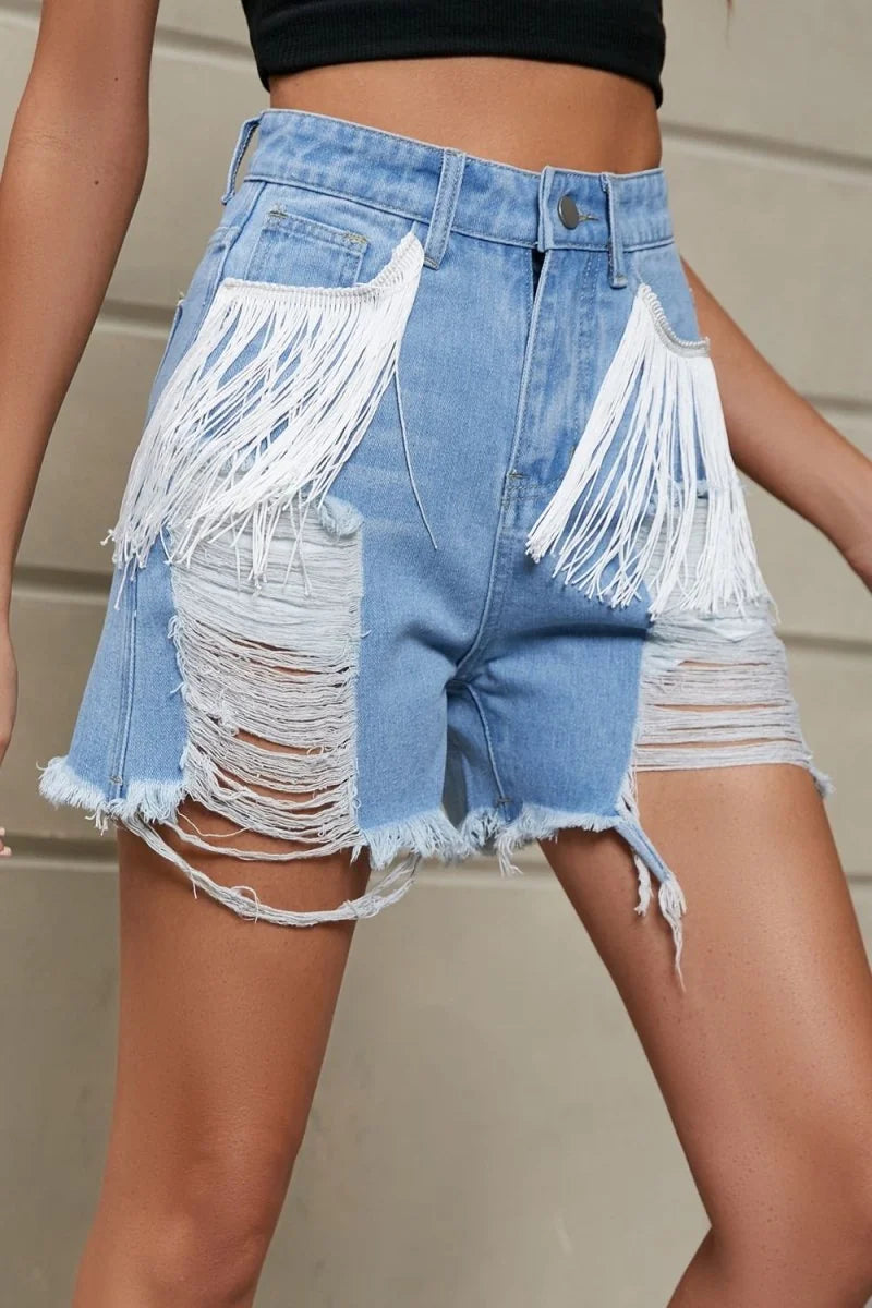 Light wash distressed denim shorts with white fringe accents on pockets and frayed hems.