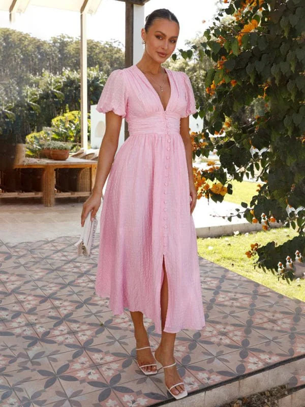 Pink textured midi dress with V-neck, puff sleeves, and button front, on a model.