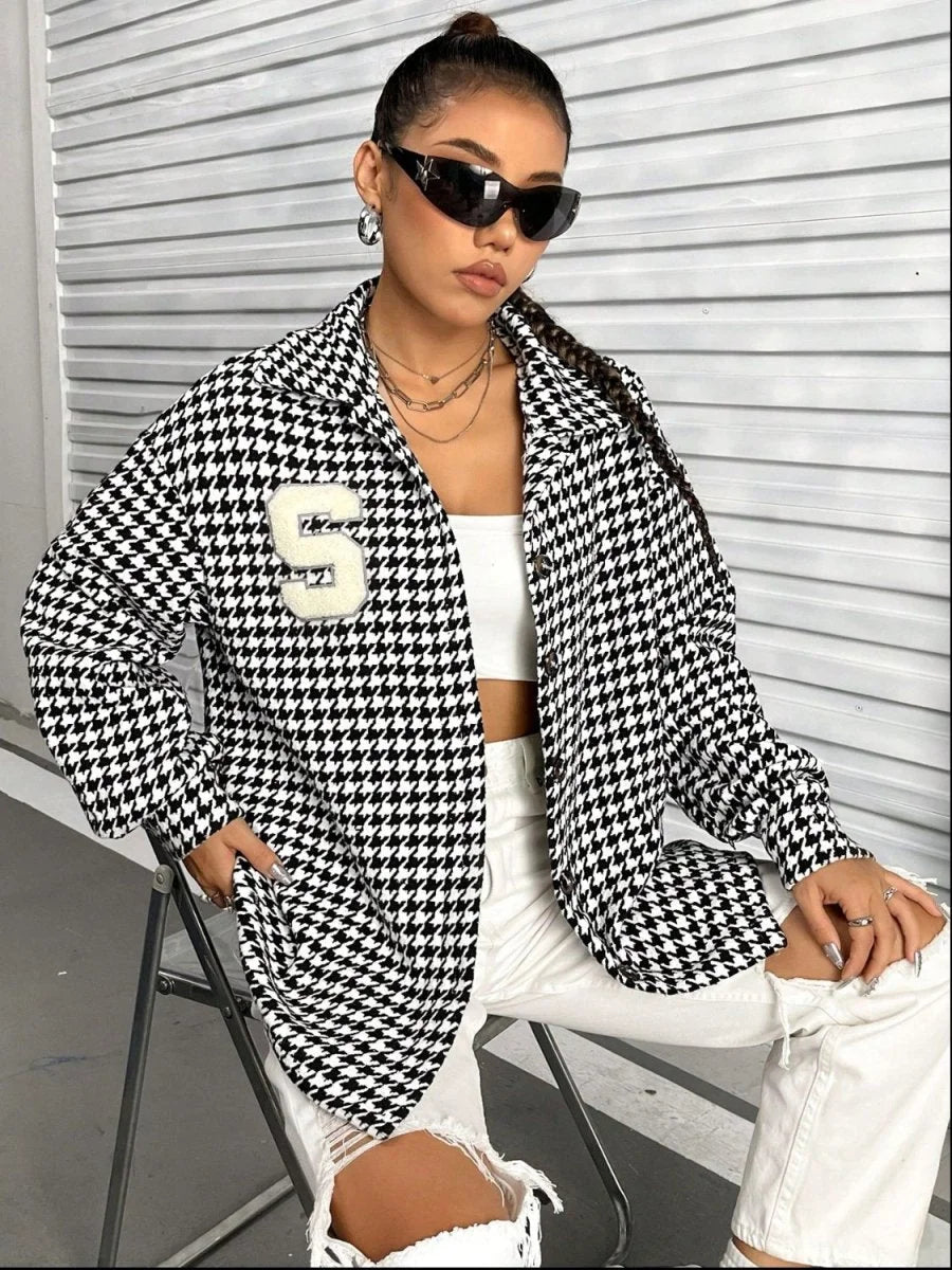 Black and white houndstooth pattern jacket with a large "S" patch on the chest.
