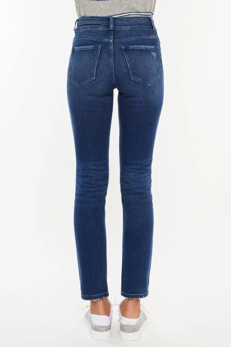 Back view of dark wash denim jeans with a distressed detail on the right back pocket and frayed hem.