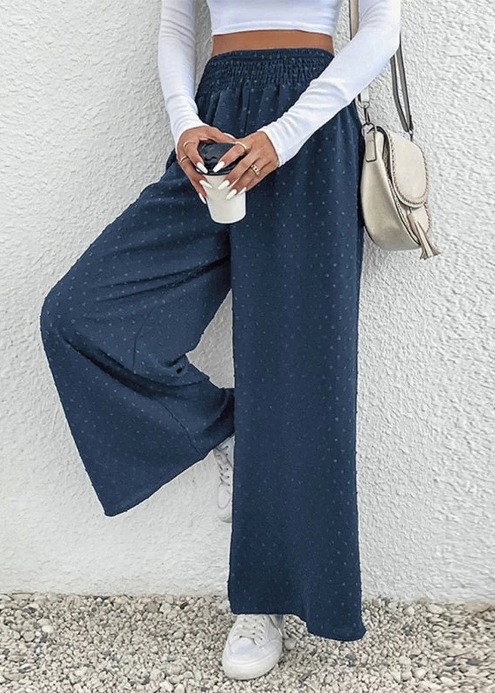 Navy blue polka dot wide-leg pants with a smocked waist and white sneakers.