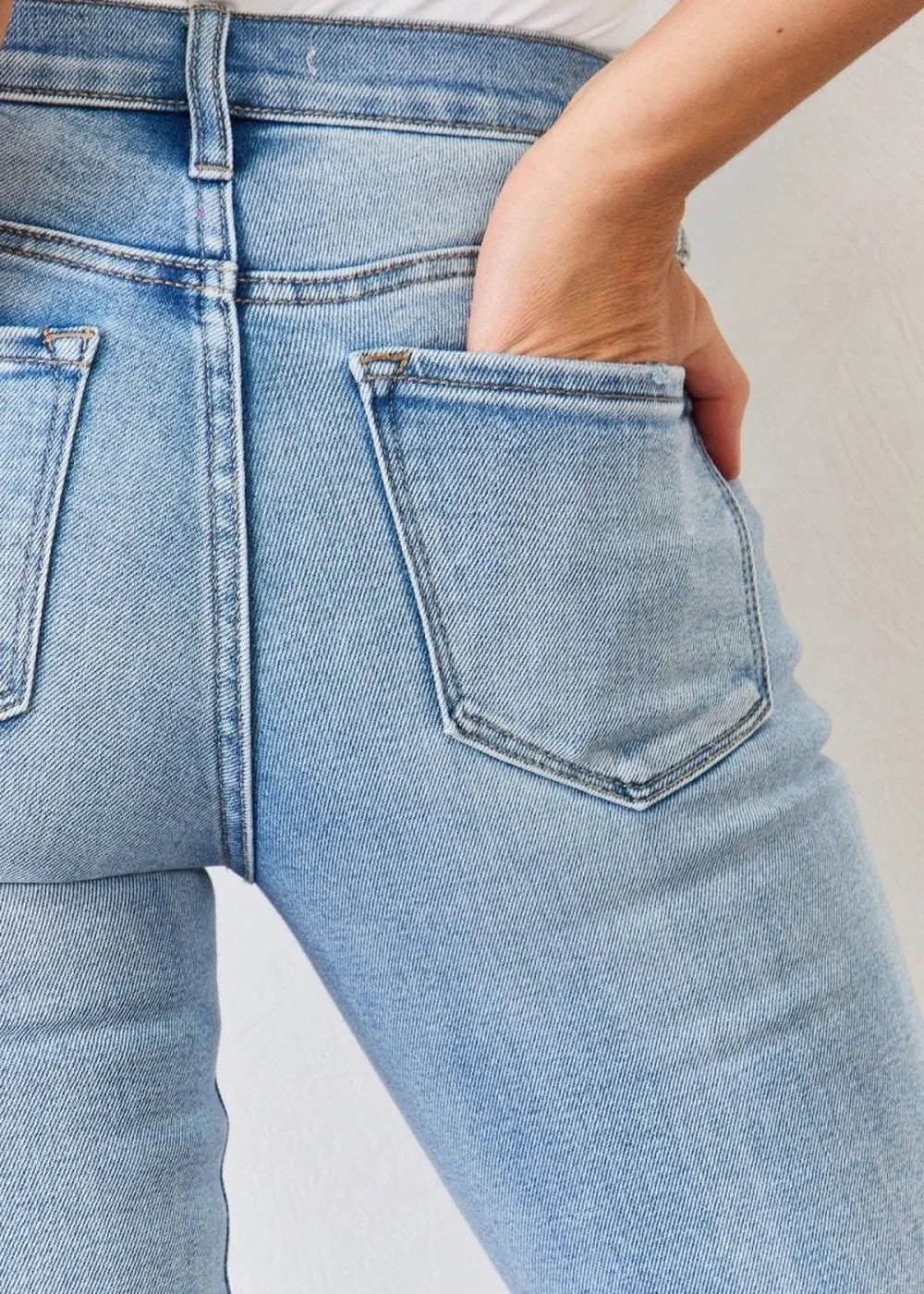 Close-up of light blue denim jeans showing back pockets and textured fabric.
