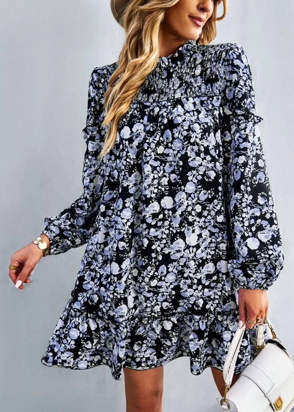 Black and blue floral print dress with smocked neckline and ruffled hem on model.