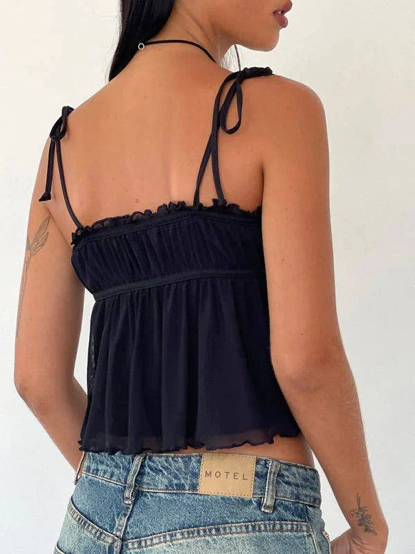 Black mesh cami with tie straps and ruffled neckline over denim jeans.