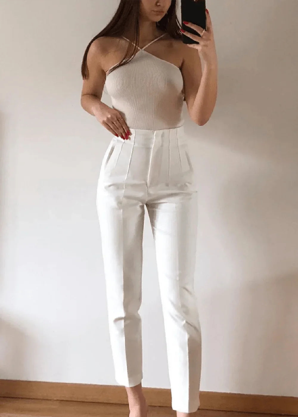 Cream high-waisted pants with a tailored fit and subtle pleats, worn by a model.