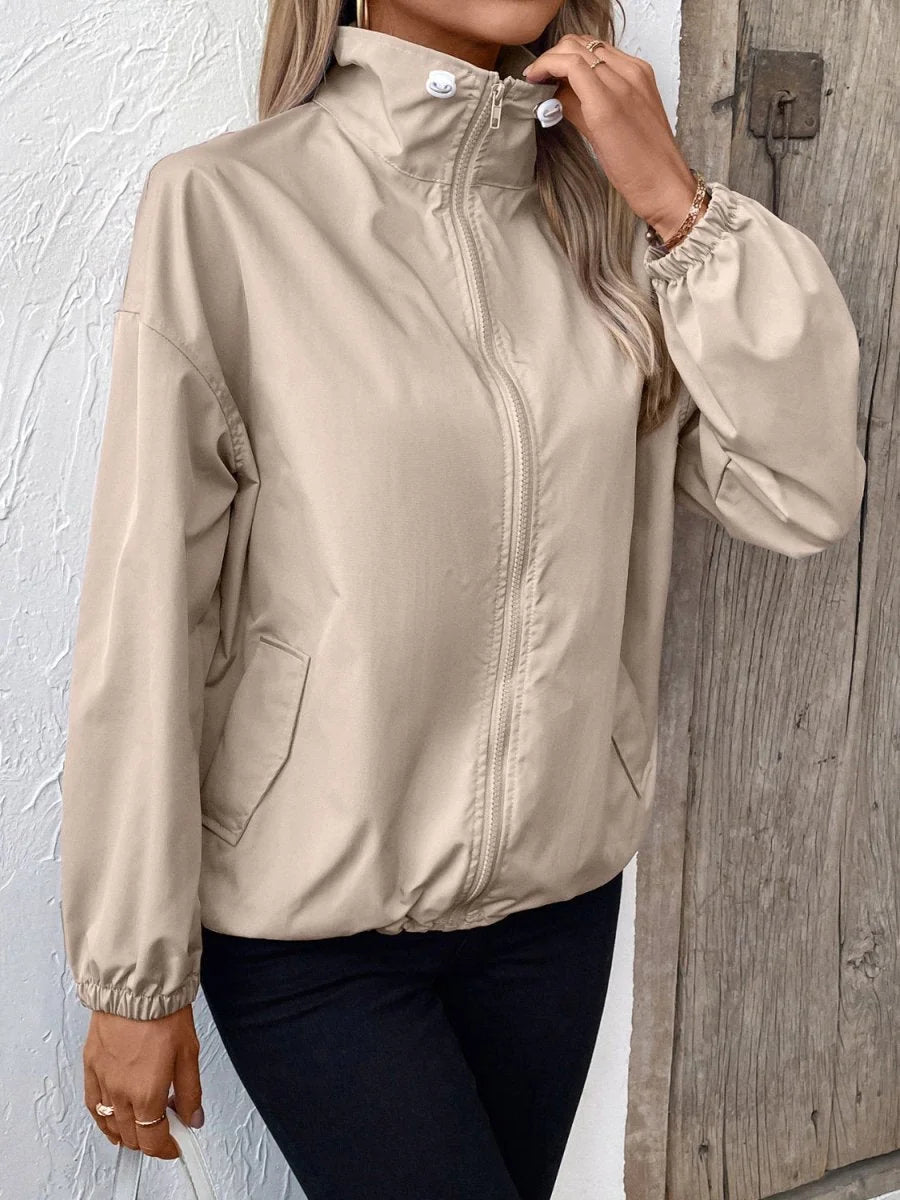 Beige polyester jacket with a mock neck, zip front, and elastic cuffs on a model.