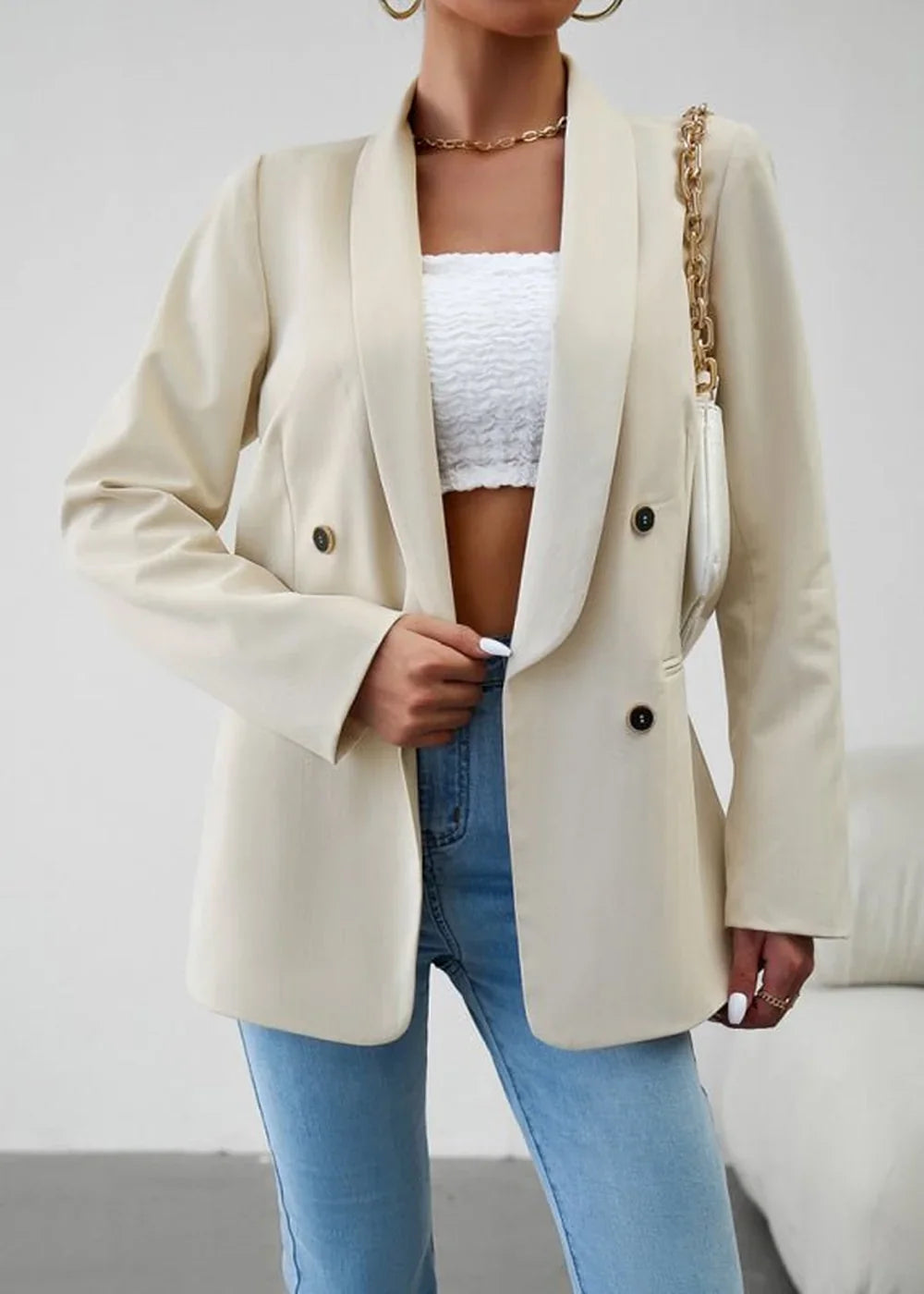 Cream double-breasted blazer with gold chain detail on purse and gold necklace on model.